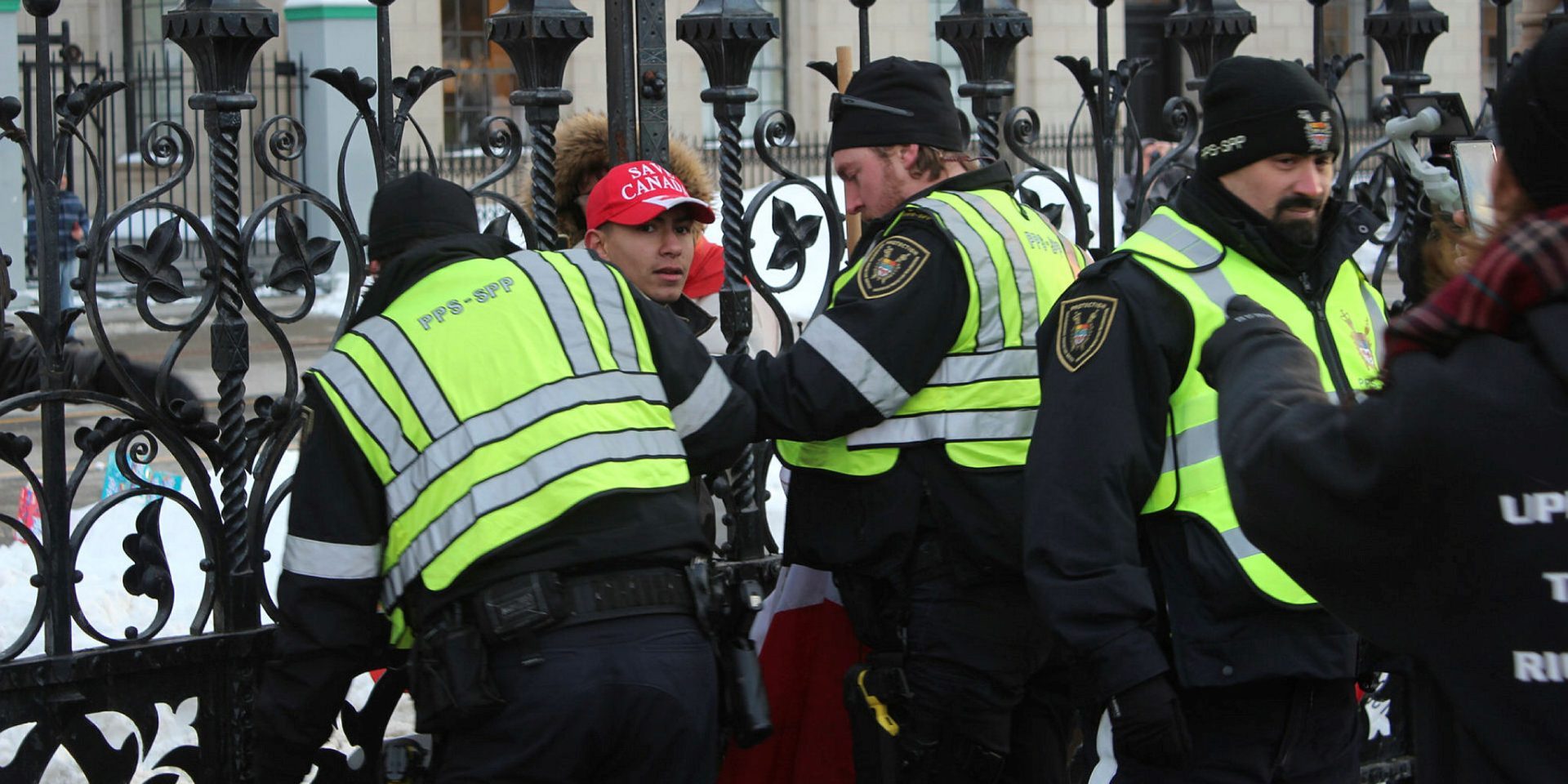 One of two protestors detained by Parliamentary Protective Services after attempting to bypass officers with a flagpole-in the hands of the PPS officer on the right-at the 'Freedom Convoy 2.0' anniversary protest on Jan. 28, 2023.