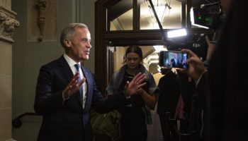 Prime Minister Mark Carney speaks with reporters before the Liberal cabinet meeting in West Block on  Oct. 21, 2025. (Audrey Champoux is to his right looking down) The Hill Times photograph by Andrew Meade
