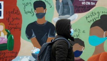 A pedestrian walks past a COVID-19 themed mural outside Ottawa City Hall  on Jan. 11, 2021