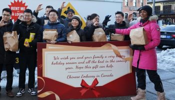 Diplomats from the Chinese Embassy make a donation to the Ottawa Food Bank on Dec. 13. The ‘C’ gesture represents both China and Canada. Photograph courtesy of the Chinese Embassy